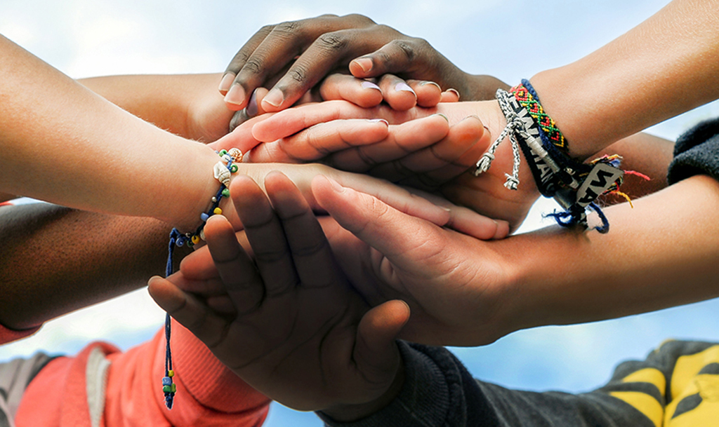 hands of a diverse group of people are stacked in a gesture of solidarity and teamwork